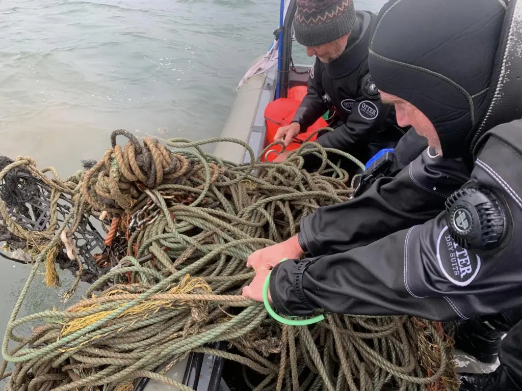 Divers hauling in ghost gear on to a vessel