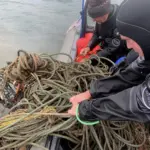 Divers hauling in ghost gear on to a vessel