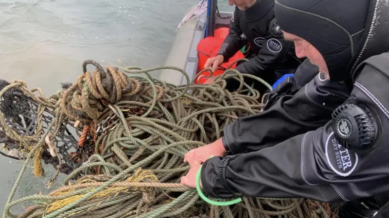 Divers hauling in ghost gear on to a vessel
